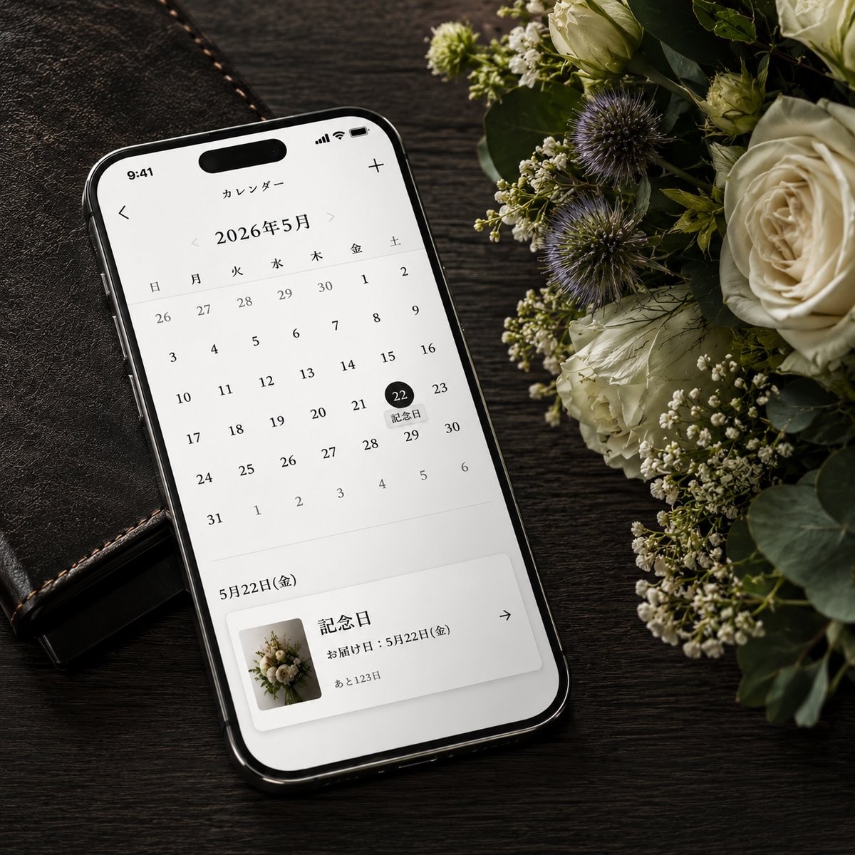 記念日が記されたスマホのカレンダーと花